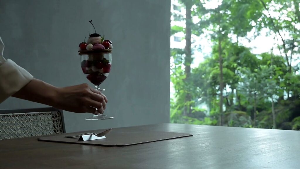 Asako Iwayanagi: Haute Pâtisserie, the Parfait Bijou and the Art of Gelato in Tokyo 10 Hand placing a cherry parfait by a window full of forest