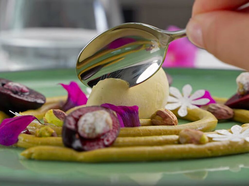 Gelato quenelle with figs and pistachio on a green plate