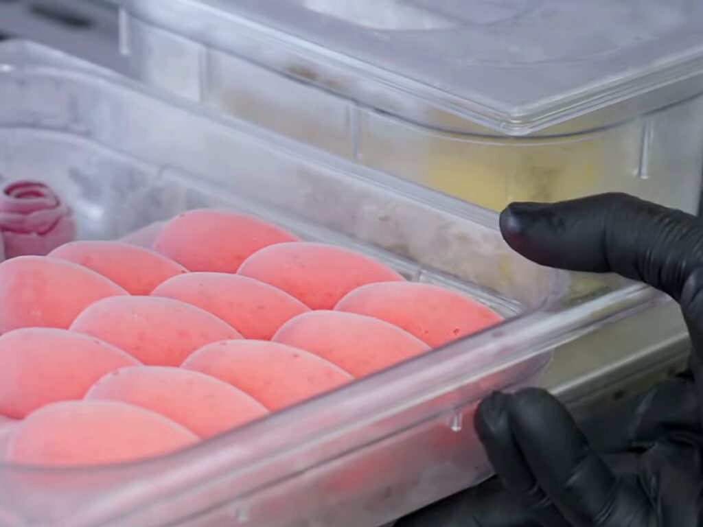 Tub of unmoulded strawberry gelato quenelles