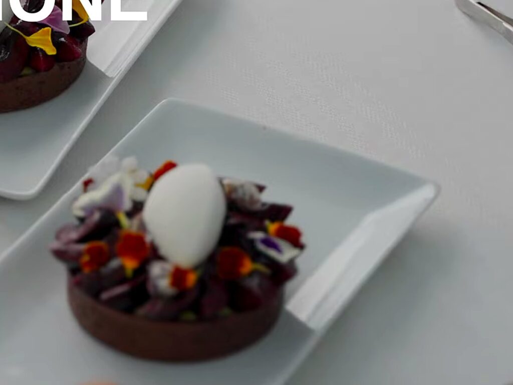 Chocolate tartlet topped with a gelato quenelle and edible flowers