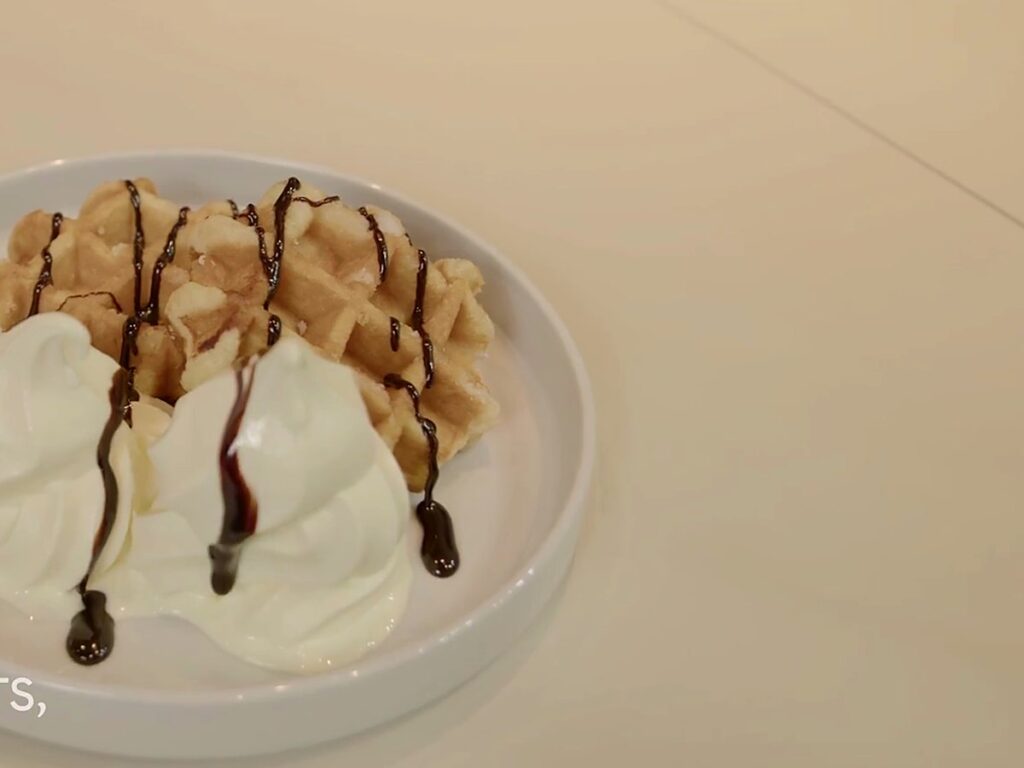 A waffle with soft serve and chocolate.